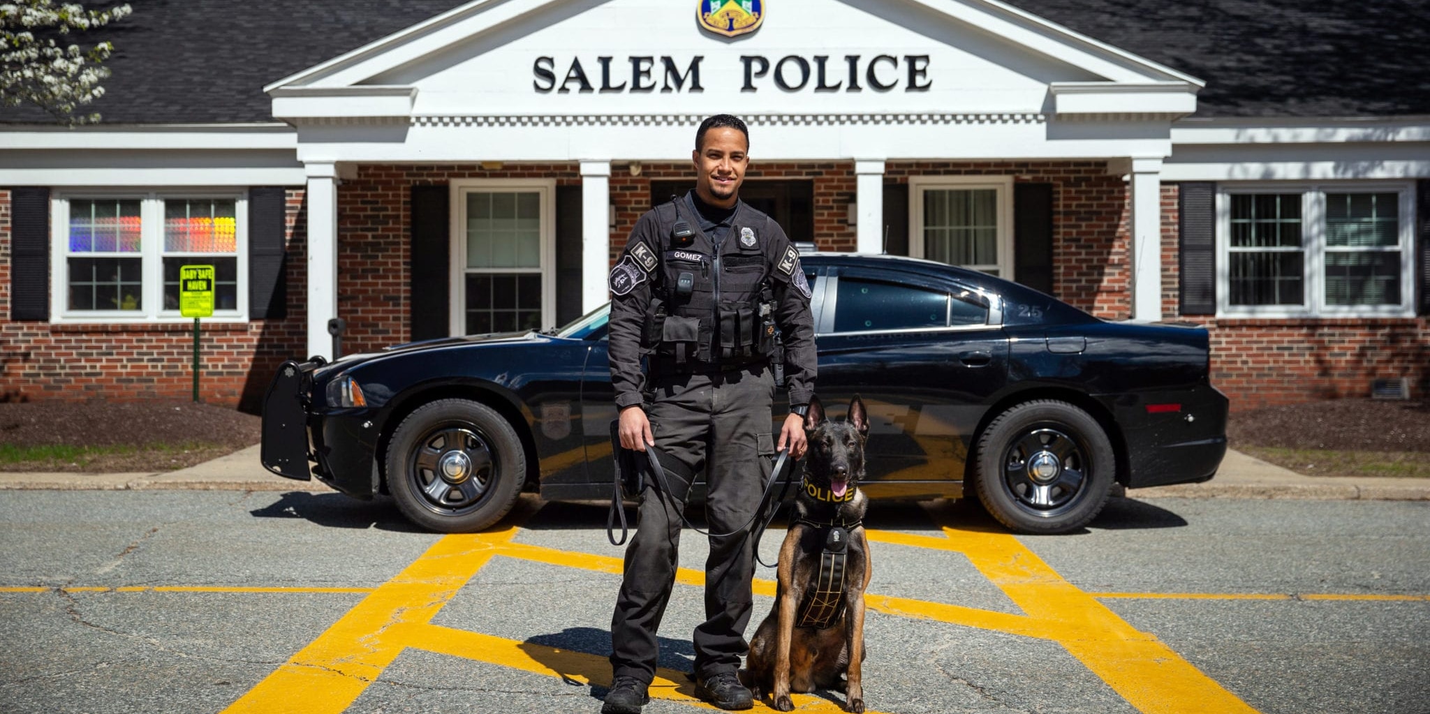 Salem K9 Officer with K9 standing in front of police cruiser and the department